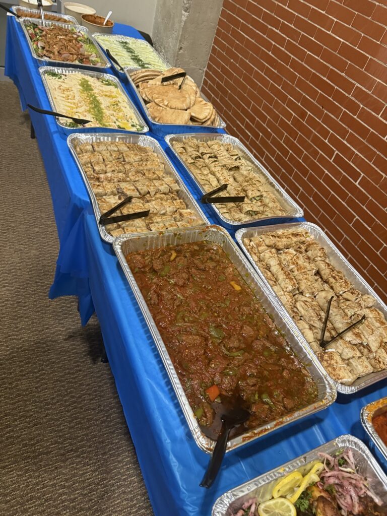 Catering buffet with hummus, pita, wraps and a tray of stew