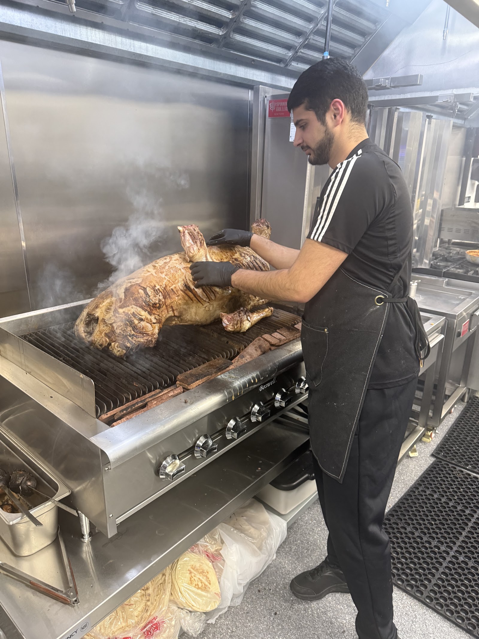 Chef grilling a whole lamb over an open flame in the kitchen